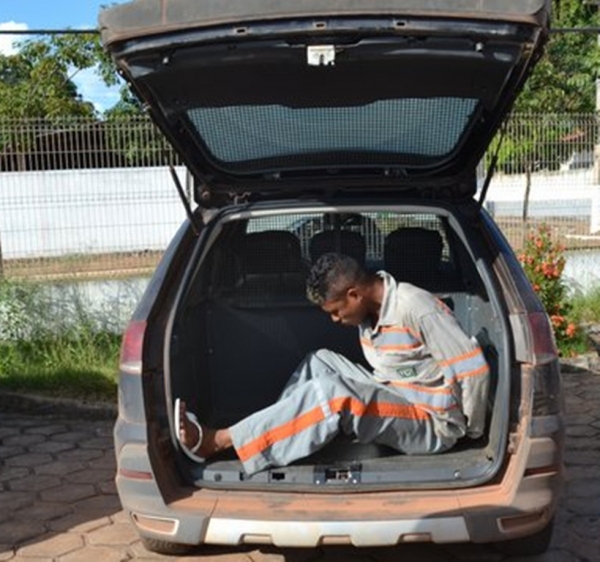 Homem usando tornozeleira eletrônica e uniforme de empresa é conduzido até a delegacia do 1º Distrito Policial de Açailândia.